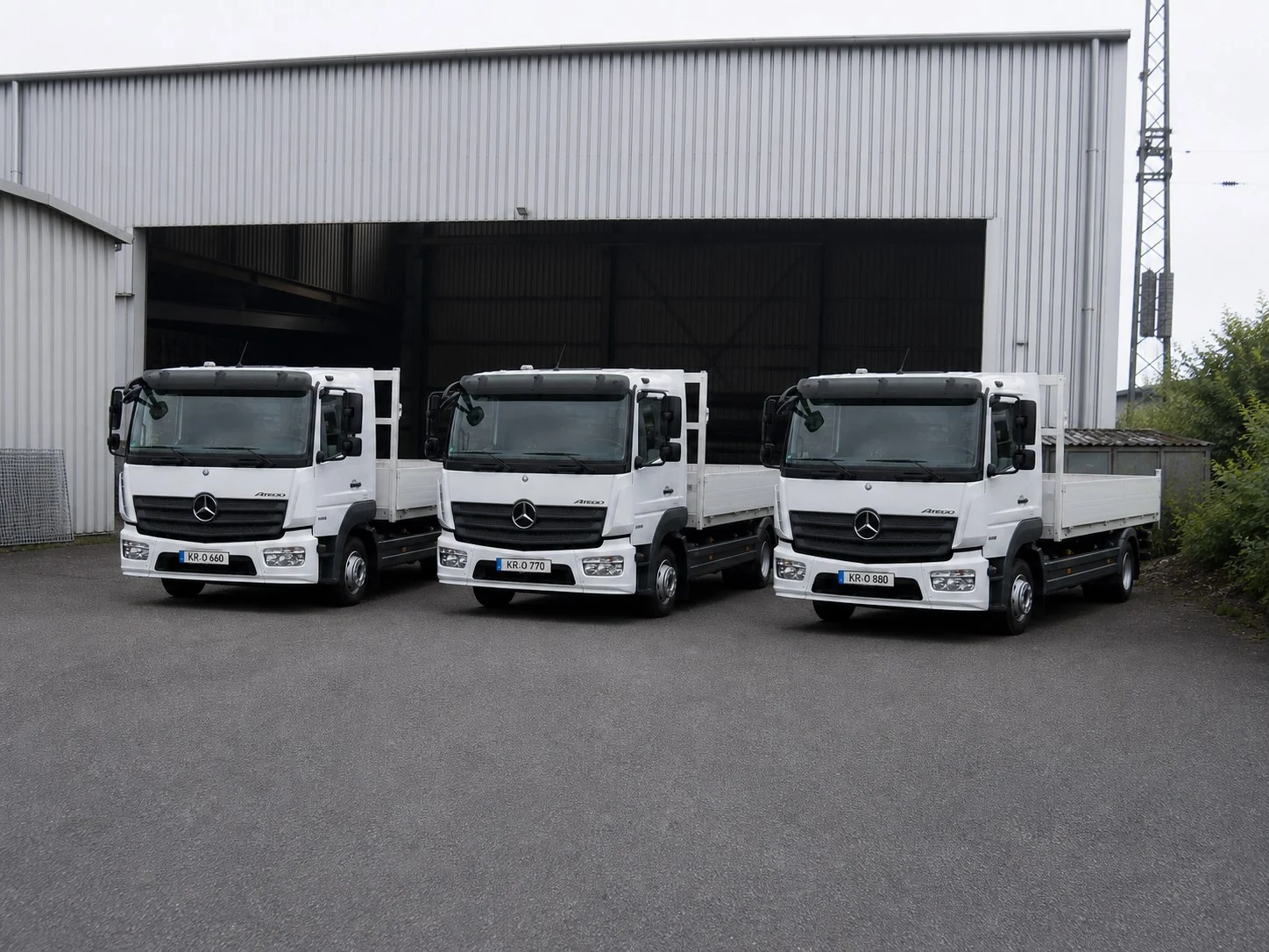 Three white Mercedes-Benz Atego trucks from the Franz Huisgen fleet in front of the warehouse