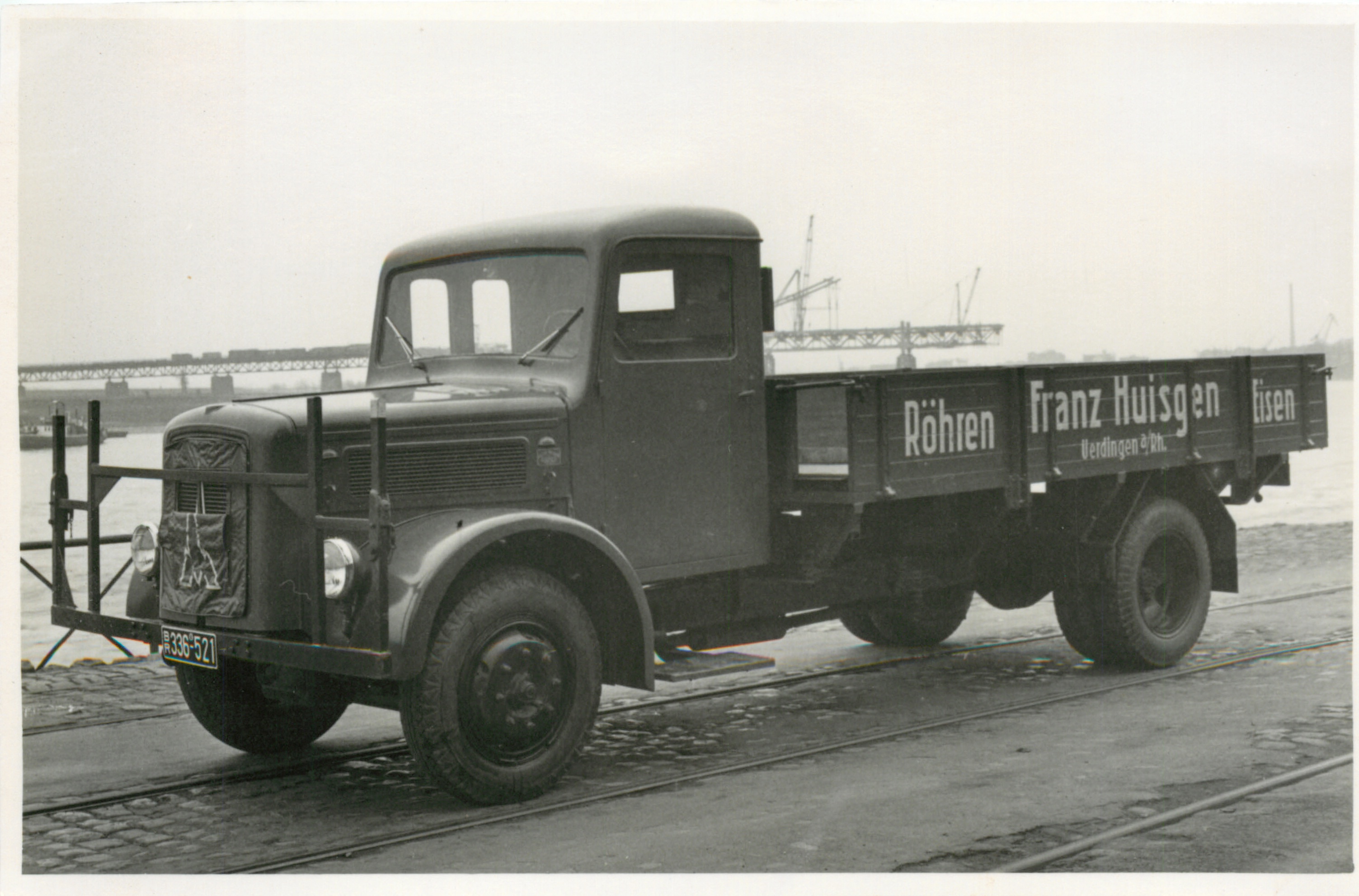 Firmen-LKW von Franz Huisgen im Uerdinger Hafen mit dem Wiederaufbau der Rheinbrücke im Hintergrund