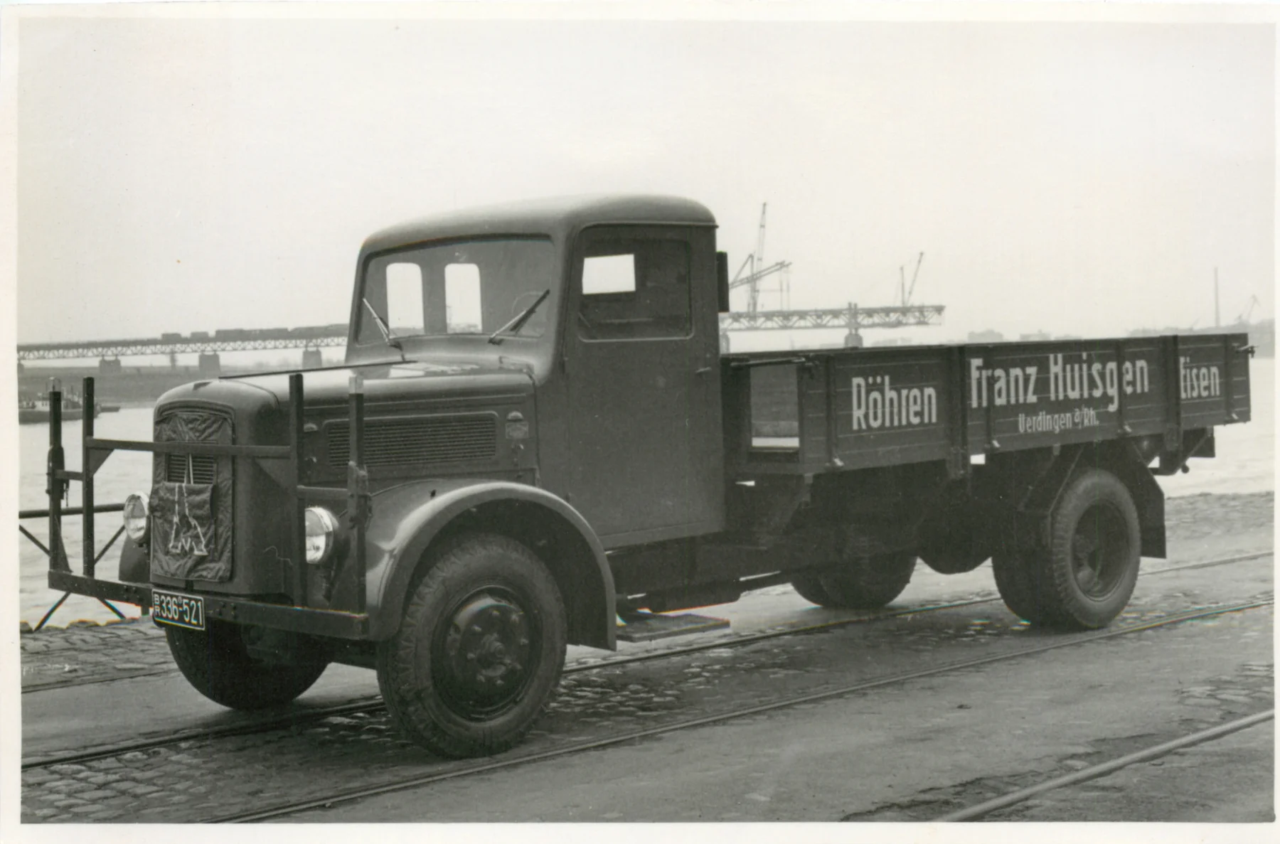 Firmen-LKW von Franz Huisgen im Uerdinger Hafen mit dem Wiederaufbau der Rheinbrücke im Hintergrund